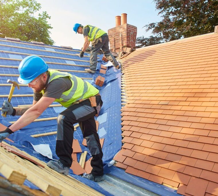 a roofer nails on the roof tiles