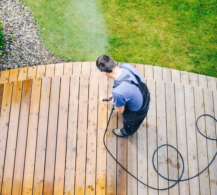 cleaning terrace with a power washer - high water pressure cleaner on wooden terrace surface