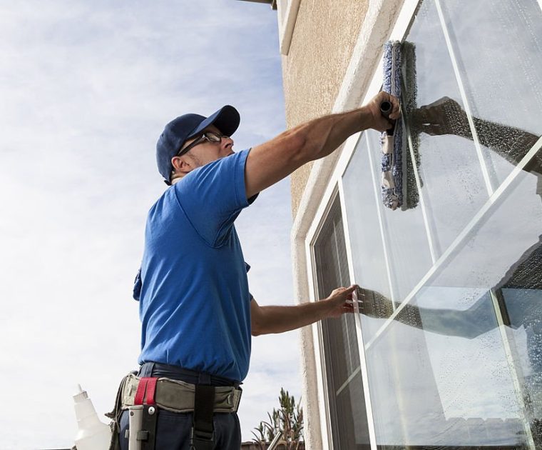 Man cleaning window of a home.